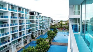 A multi-story hotel with balconies, a swimming pool, and a view of the sea. - D606 Bright 2-bedroom apartment with Playground near Sea, city (Huahin)