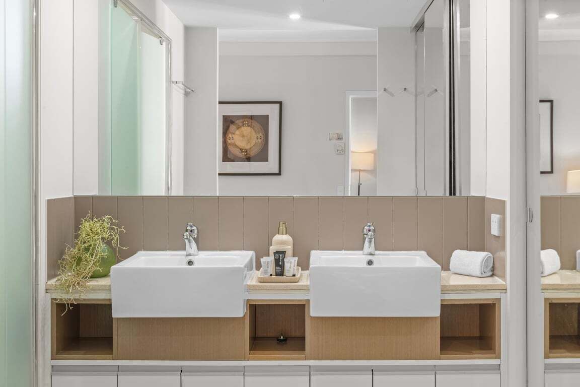 A modern bathroom with two sinks, a mirror, and a framed picture on the wall.