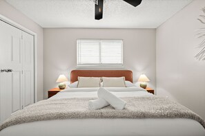 A bedroom with a bed, two bedside lamps, a window with blinds, a ceiling light, and a door. - Stylish King Suite~Pool~Fast Wi-Fi~Near Austin (Round Rock)