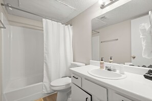 A bathroom with a bathtub, toilet, sink, and mirror. - Stylish King Suite~Pool~Fast Wi-Fi~Near Austin (Round Rock)