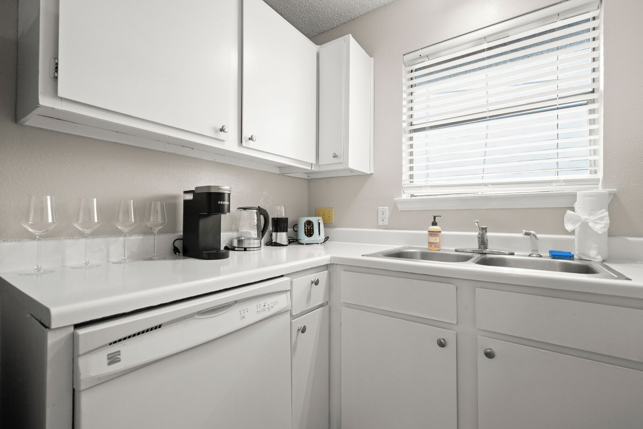 A kitchen with white cabinets, a coffee maker, a toaster, and a sink.