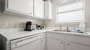 A kitchen with white cabinets, a coffee maker, a toaster, and a sink.