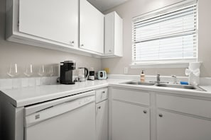 A kitchen with white cabinets, a coffee maker, a toaster, and a sink.