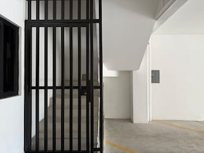 Ein begrenzter Zugang zu einem Parkplatz mit Betonboden und einer weißen Wand.