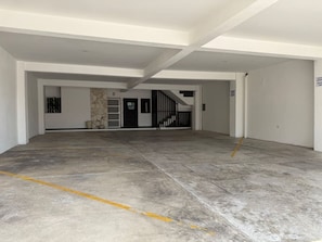 Eine leere Parkgarage mit Betonboden, einer Treppe und einer Tür mit einem Schild.