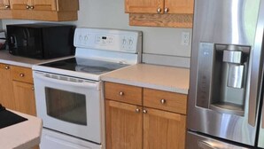 A kitchen with wooden cabinets, a stainless steel refrigerator, a microwave, an oven, and a coffee maker. - Gamma
A beautiful master bedroom with bathroom in a town house. (Fort McMurray)