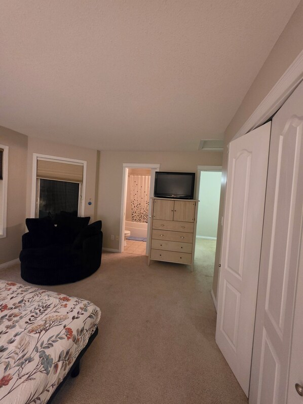 A bedroom with a bed, a dresser, a television, and a chair.