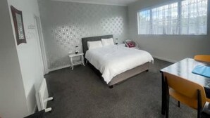 A bedroom with a bed, bedside table, and a window. - Mitchell's Bay BnB (Riverton / Aparima)