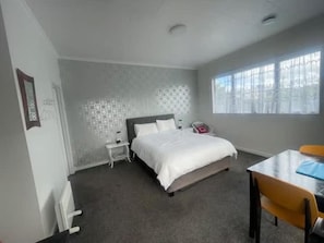 A bedroom with a bed, bedside table, and a window.
