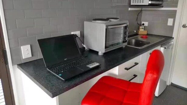 A kitchenette with a laptop, a microwave, and a red chair. - Mitchell's Bay BnB (Riverton / Aparima)