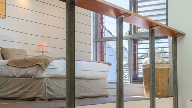 A loft bedroom with a bed on the lower level and a window overlooking the street. - Sunny Balcony, Luxury in the Heart Of Bondi Beach (Bondi Beach)