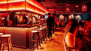 A bar area with stools and tables, a bartender, and patrons. - Sunny Balcony, Luxury in the Heart Of Bondi Beach (Bondi Beach)