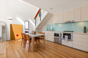 Eine moderne Küche mit Essbereich, ausgestattet mit einem Holztisch, Stühlen, einem Einbauofen und einer Mikrowelle.