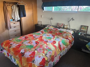 Ein Schlafzimmer mit Bett, Kleiderschrank, Schreibtisch und Fenster.