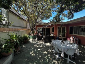 Un'area patio con un tavolo da pranzo, sedie e piante in vaso.