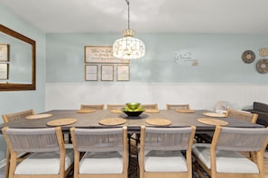 Ein Esszimmer mit rundem Tisch, Stühlen, einer Chandelier und Wanddekorationen.