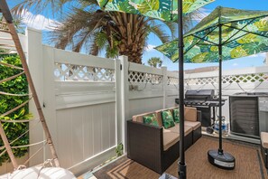 Eine Terrasse im Freien mit Grill, Sitzbereich und weißem Zaun.