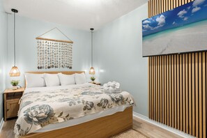 Ein Schlafzimmer mit einem Bett, Nachttischen, einer Wandleuchte und einem Wandbild.