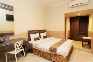 Una habitación de hotel con cama, escritorio, silla y armario.