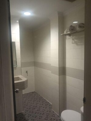 Un baño con ducha, lavamanos e inodoro.