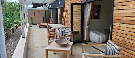 A covered outdoor seating area with wooden furniture and a large sliding glass door.