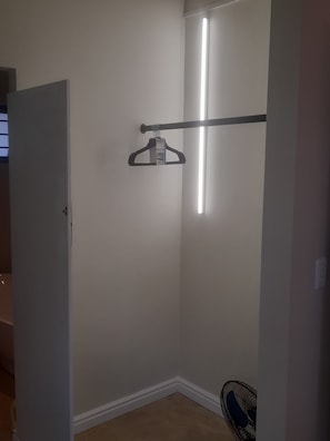 Ein Zimmer mit Tür, Kleiderhaken, Wandleuchte und Deckenventilator.