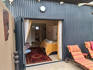 Quarto compacto com cama, mesa pequena e cadeira.