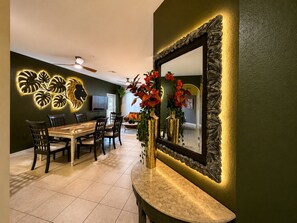 A dining area with a table, chairs, a mirror, and decorative wall art. - 3 BR | Free water park | 5 min from Disney (Kissimmee)