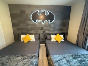 A hotel room with two beds, a wall-mounted Batman logo, and a window with curtains. - 3 BR | Free water park | 5 min from Disney (Kissimmee)