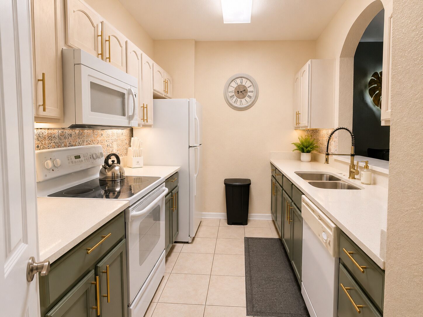 A modern kitchen with white appliances, green cabinets, and a clock on the wall.