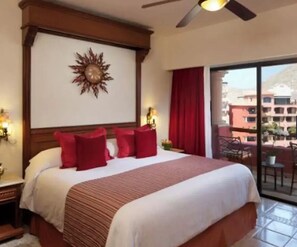 Ein Hotelzimmer mit einem großen Bett, einem Deckenventilator, einer Sonnendekoration und Blick auf den Außenbalkon.