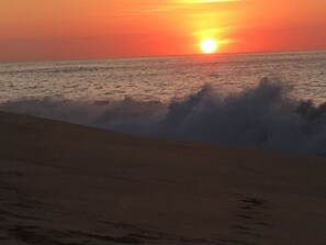 A sunset over the ocean with waves crashing onto the shore. -  Playa Grande Penthouse 2-Bedroom Suite on the Ridge Christmas & New Years weeks (Cabo San Lucas)