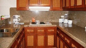 Eine Küche mit Granit Arbeitsplatten, Holzschränken, einer Edelstahlspüle und einem eingebauten Herd.