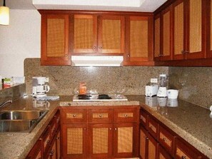 A kitchen with granite countertops, wooden cabinets, a stainless steel sink, and a built-in stove. -  Playa Grande Penthouse 2-Bedroom Suite on the Ridge Christmas & New Years weeks (Cabo San Lucas)