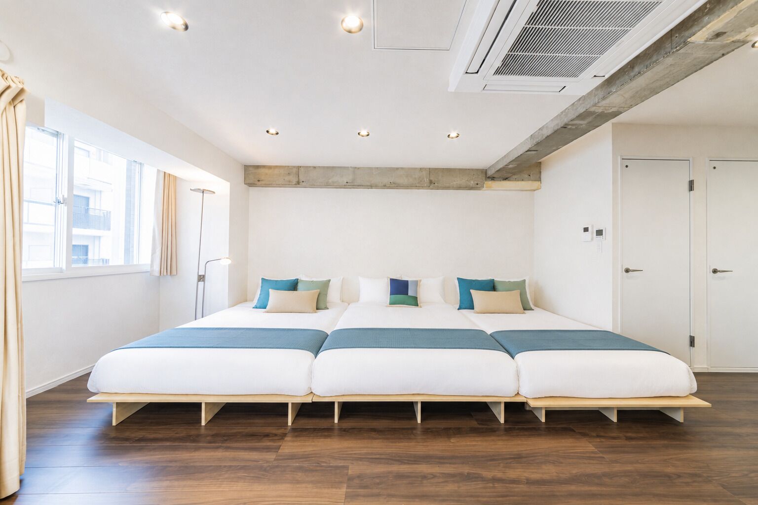 Una habitación de hotel moderna con una cama grande, suelo de madera y vistas a la ciudad.