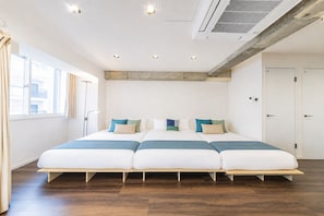 Quarto de hotel moderno com uma cama grande, piso de madeira e vista para a cidade.