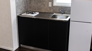 A kitchen with a black countertop, a white sink, and a white refrigerator. - AS7 Building (Sumida-ku)