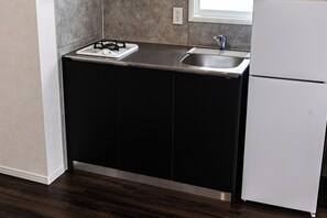 Una cuina amb un taulell negre, un rentaplat de color blanc i un frigorífic blanc.