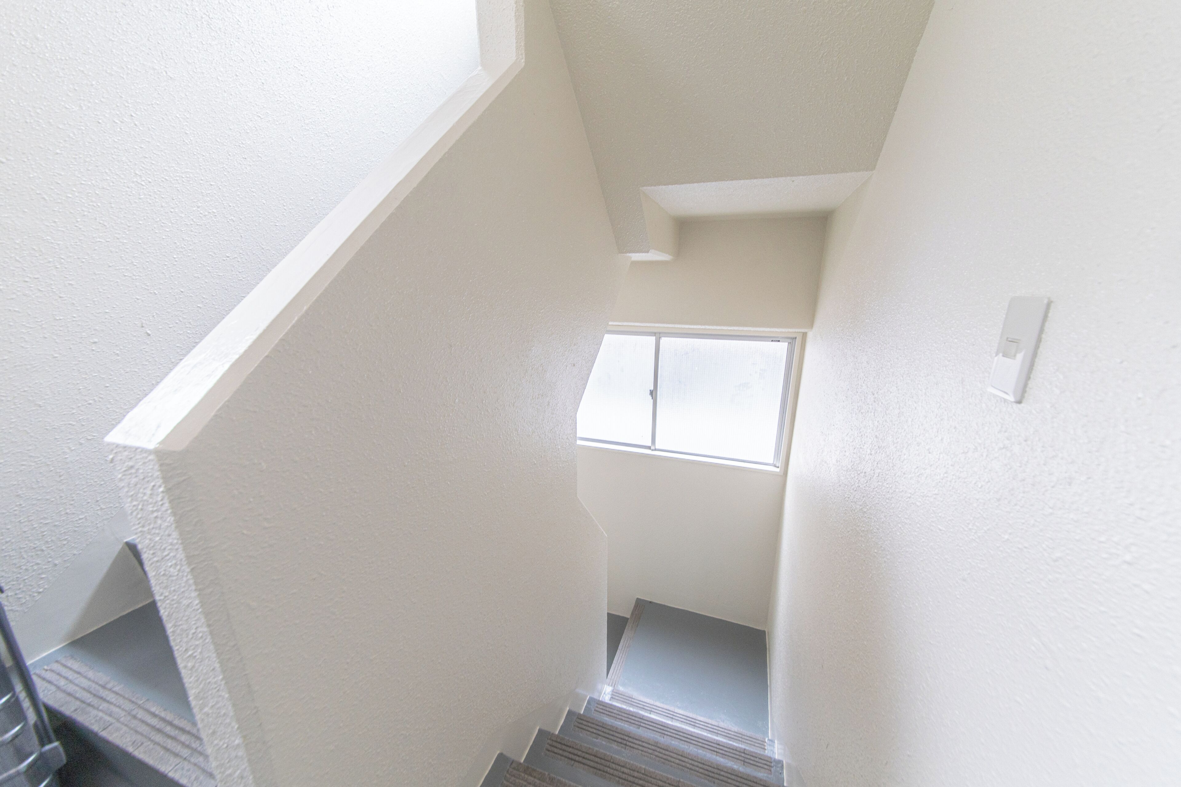 Una escalera con barandilla que conduce a un rellano con ventana.