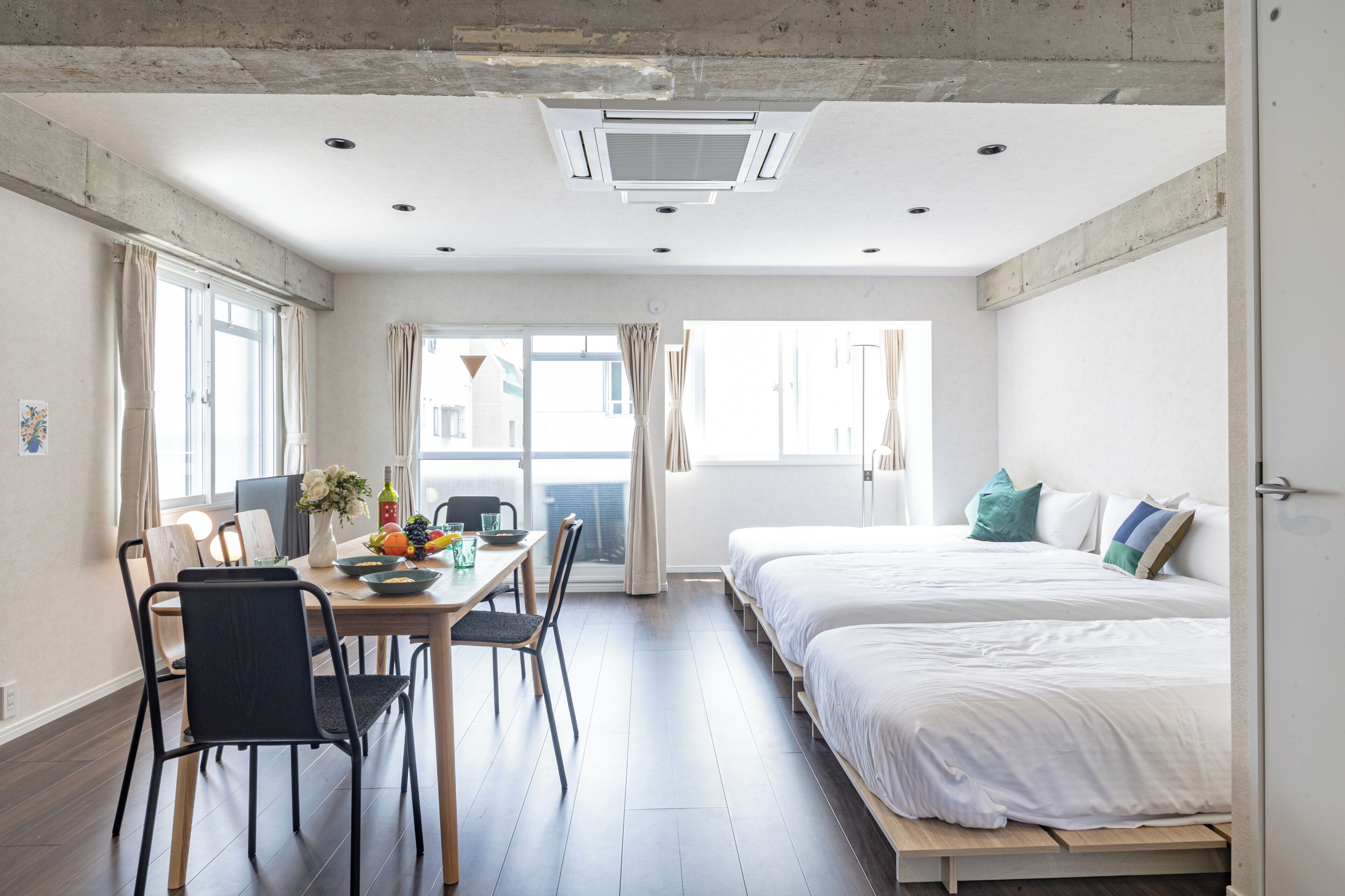 Habitación de hotel moderna con comedor, cama con almohadas y vistas por la ventana.