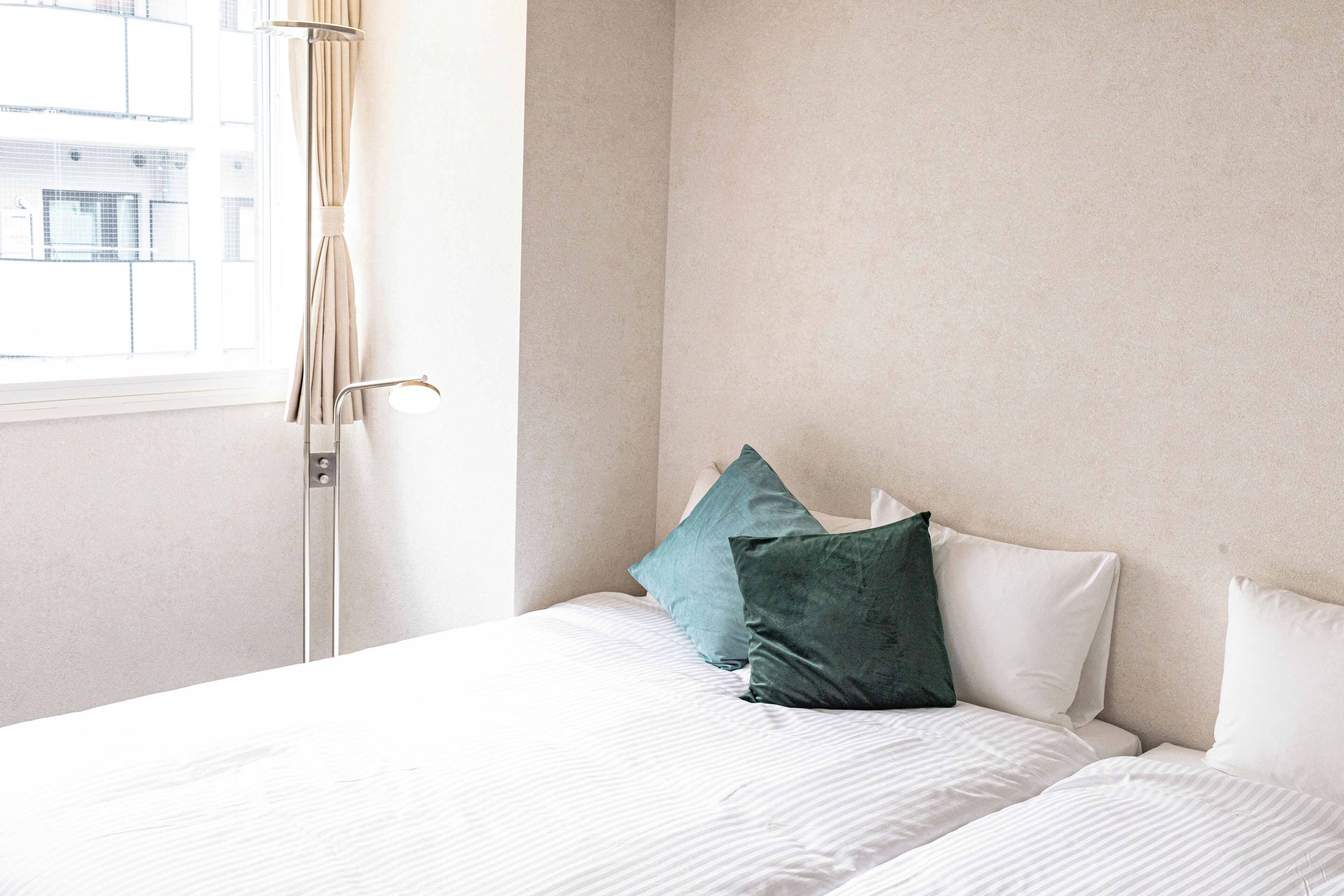 Ein Schlafzimmer mit Bett, Kissen, einem Fenster und Vorhängen.