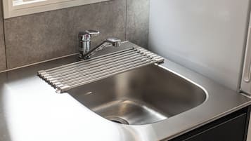 Un évier de cuisine en acier inoxydable, doté d’un robinet moderne et d’un égouttoir intégré.