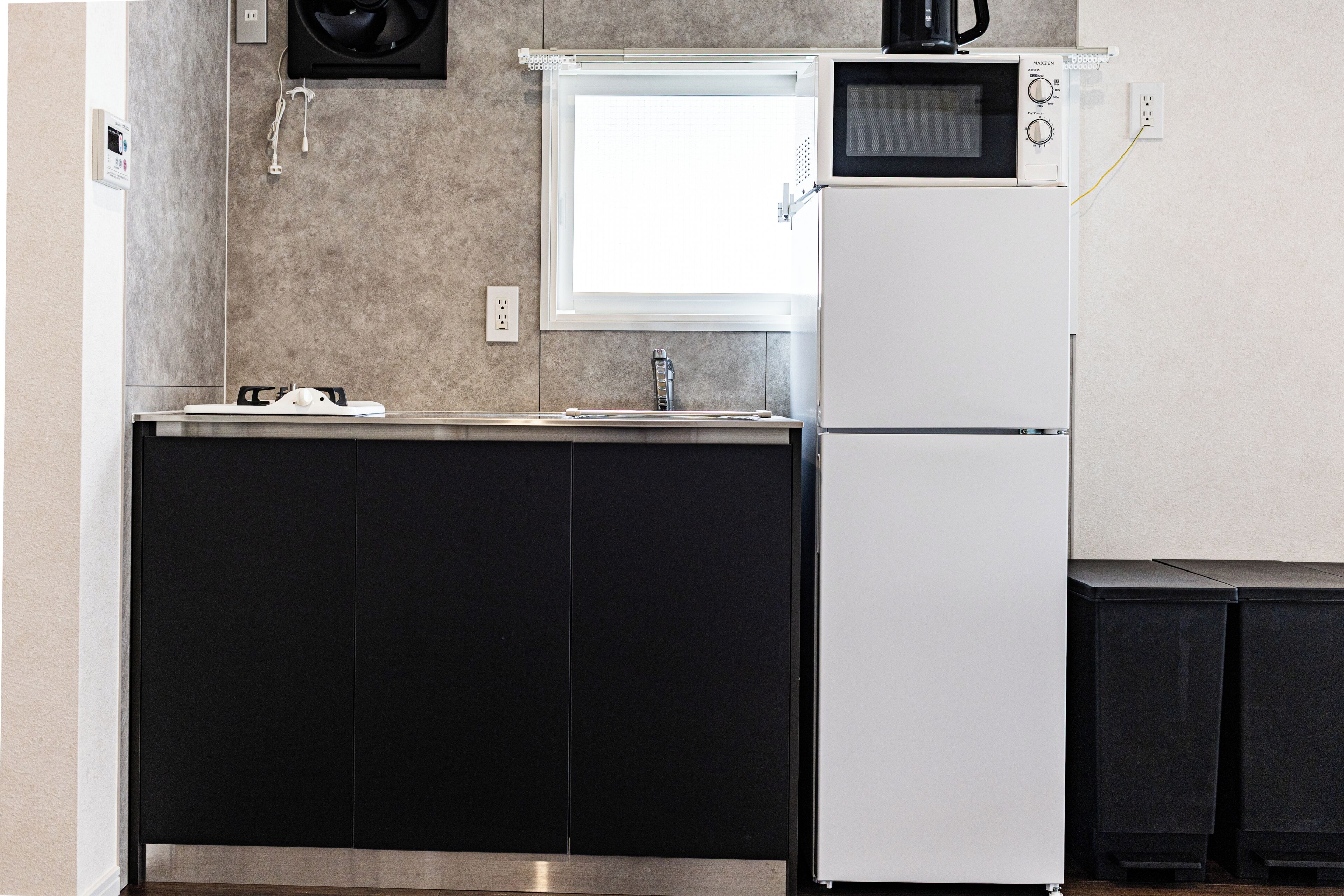 Una cocina compacta con microondas, pileta y refrigerador.