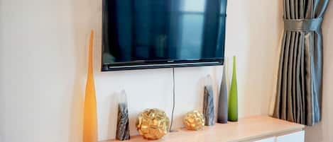 A flat-screen TV mounted on a wall above a wooden console with decorative items.