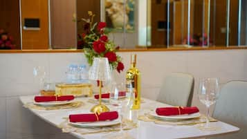 A dining table set with red napkins, gold cutlery, and a bottle of champagne.