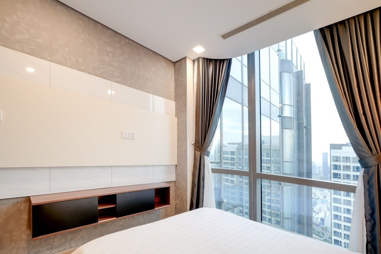 A hotel room with a large window, a bed, a built-in TV, and a wall-mounted shelf.