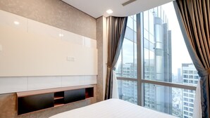 A hotel room with a large window, a bed, a built-in TV, and a wall-mounted shelf. - Landmark 81 Serviced Apartment - Mariana (Ho Chi Minh City)