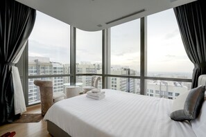 A hotel room with a large bed, a round table, a chair, and a view of the cityscape through large windows. - Landmark 81 Serviced Apartment - Mariana (Ho Chi Minh City)