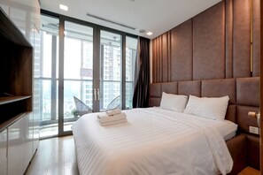 A modern hotel room with a large bed, a TV, and a view of the city through floor-to-ceiling windows. - Landmark 81 Serviced Apartment - Mariana (Ho Chi Minh City)