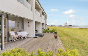 A modern building with a wooden deck, outdoor seating, and a view of the water. - Beautiful home in Ebeltoft with WiFi (Ebeltoft)